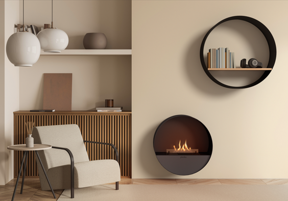 Minimalist living space with a round wall-mounted fireplace emitting small flames, a circular black shelf holding books, a beige armchair, wooden cabinetry, and modern pendant lights.